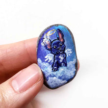 Load image into Gallery viewer, a small beach stone painted with dog art: a black french bulldog as an angel in the clouds. available as a stone keepsake or a pendant necklace