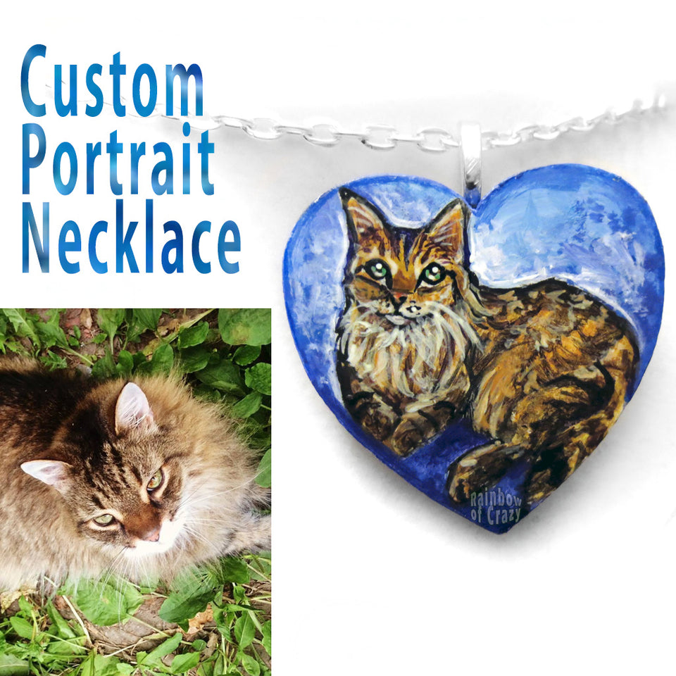 a wood heart custom painted blue with a brown and orange cat, handmade into a necklace