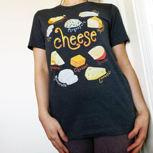 Load image into Gallery viewer, A woman is wearing the Cheese Lovers Unisex Premium T-shirt in dark grey heather, which includes art of 10 types of cheese.
