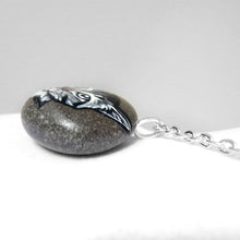 Load image into Gallery viewer, the side of a hand painted on a beach stone with the portrait of a grey tabby cat, shown as a pendant necklace