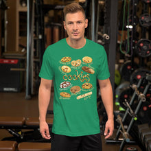 Load image into Gallery viewer, A man wearing the Happy Cookies Premium Unisex T-Shirt in the colour kelly green, featuring art of ten different types of cookies with smiling faces