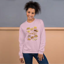 Load image into Gallery viewer, A woman is wearing the Happy Cookies Unisex Sweatshirt in the colour light pink, which features art of 10 different types of cookies with smiley faces