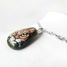 Load image into Gallery viewer, a small beach rock painted with of an orange tabby cat with golden yellow eyes, available as either a keepsake or a pendant necklace