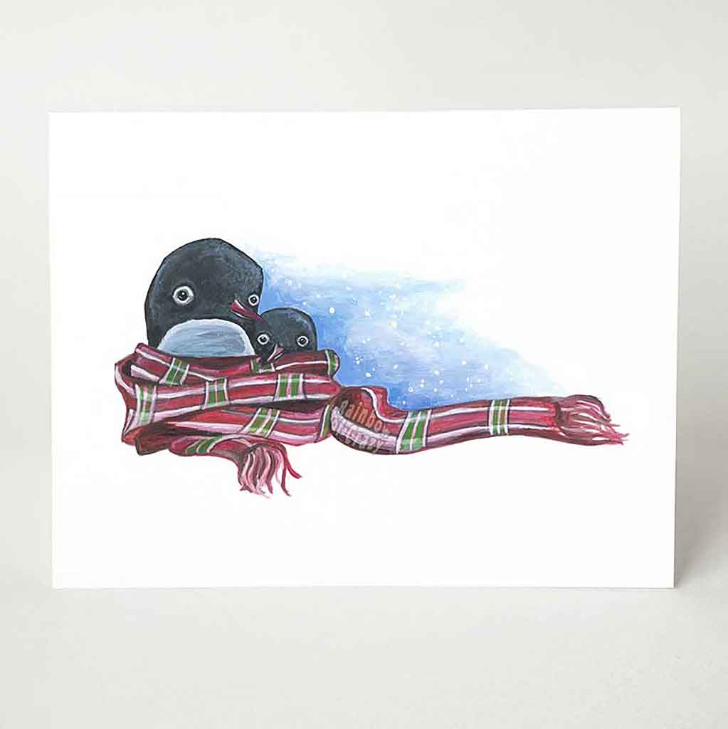 A holiday card with art of a penguin and baby penguin, with a large red plaid scarf wrapped around them.