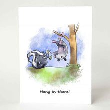 Load image into Gallery viewer, a greeting card printed with an illustration of a skunk holding out a flower towards a possum hanging upside down, with the text, &quot;Hang in there!&quot;
