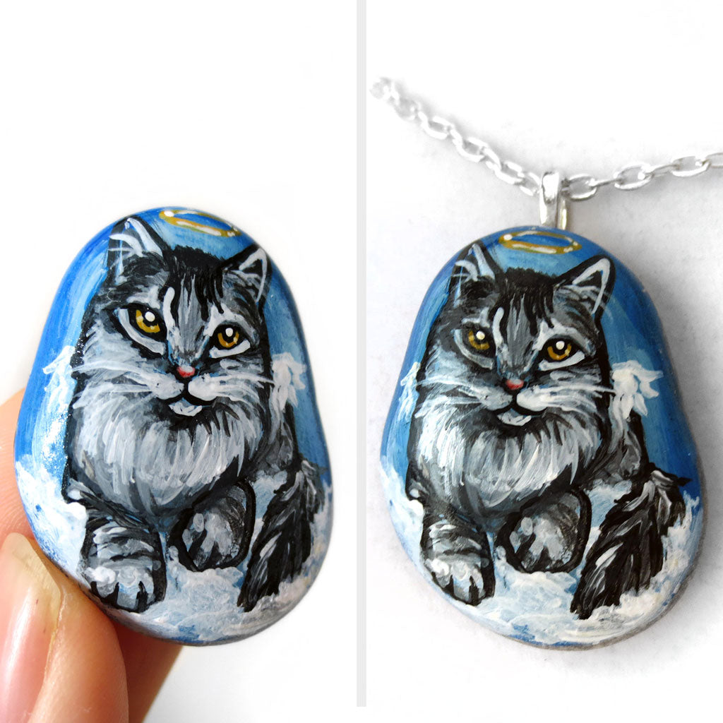 art of a silver gray maine coon cat as an angel, is hand painted on a river rock, and is available as either a keepsake or a pendant necklace