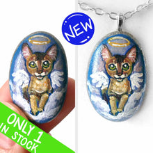 Load image into Gallery viewer, art of an Abyssinian cat, painted as an angel in the clouds. hand painted on a beach stone, available as a keepsake or pendant necklace 
