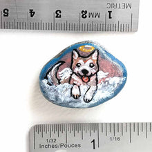 Load image into Gallery viewer, a small smooth beach stone, hand painted with the portrait of an akita dog, painted as an angel, it peers out over fluffy clouds against a blue and pink sky. this piece is available as a keepsake or pendant necklace
