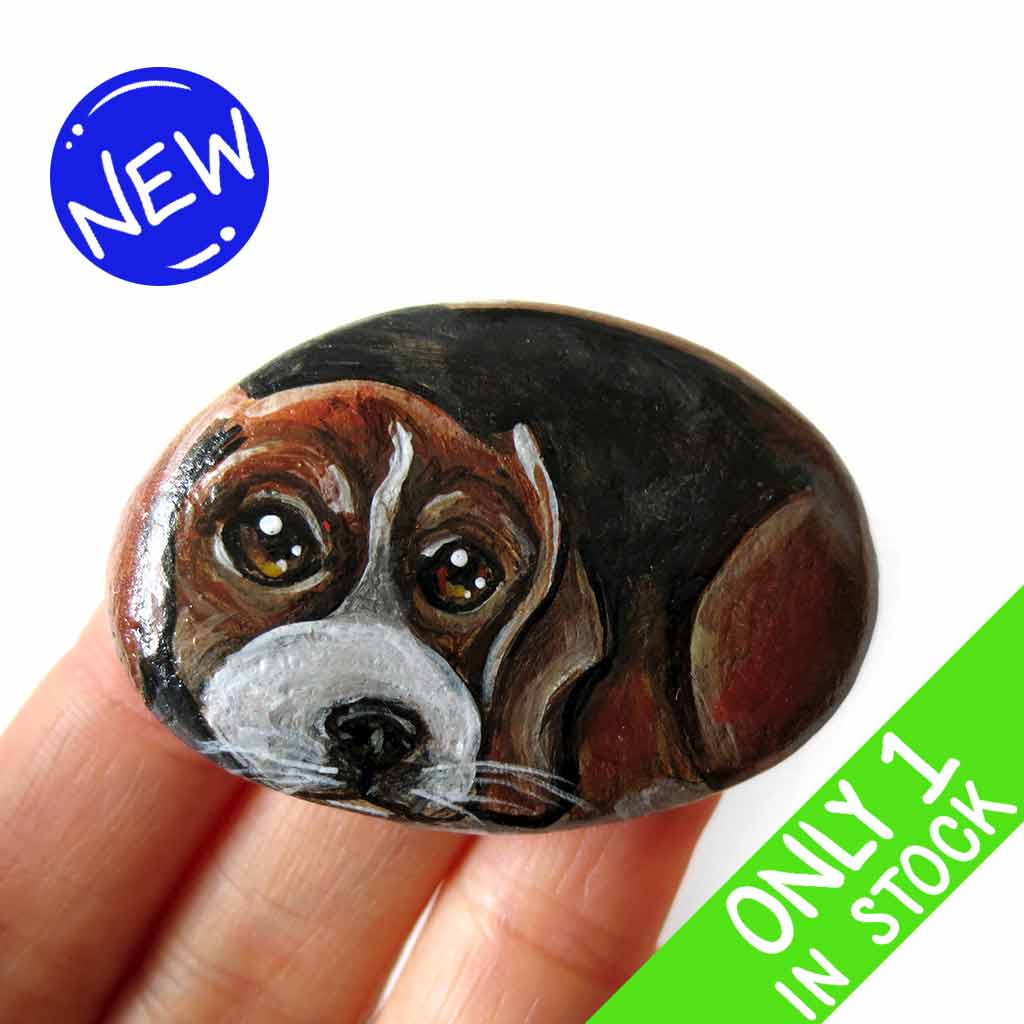 small beach stone hand painted with the portrait of a beagle, compete with paws underneath