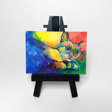 Load image into Gallery viewer, an aceo sized painting featuring a birman cat painted with rainbow colours. the painting sits on a tiny black easel
