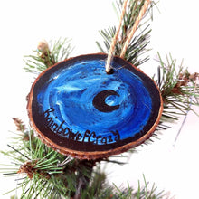 Load image into Gallery viewer, a wood slice ornament, hand painted with the silhouette of a black cat, curled up on a crescent moon, against a dark blue background. the back is painted in blacks and blues, with a small black crescent moon. signed with, RainbowofCrazy
