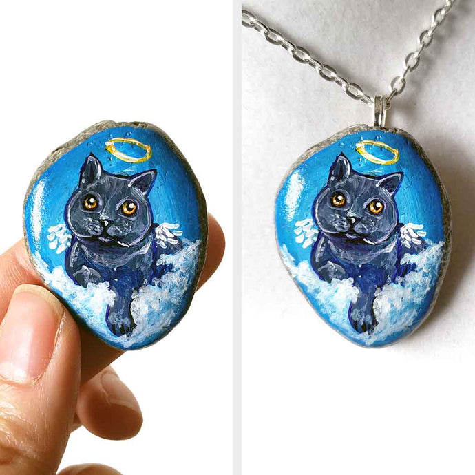 art of a dark gray / black british shorthair cat as an angel, is hand painted on a river rock, and is available as either a keepsake or a pendant necklace