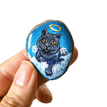 Load image into Gallery viewer, art of a dark gray / black british shorthair cat as an angel, is hand painted on a river rock, and is available as either a keepsake or a pendant necklace
