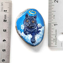 Load image into Gallery viewer, art of a dark gray / black british shorthair cat as an angel, is hand painted on a river rock, and is available as either a keepsake or a pendant necklace
