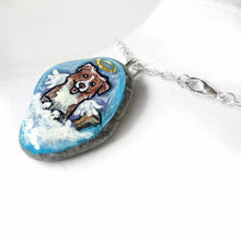 Load image into Gallery viewer, a small beach stone, hand painted with the portrait of a smiling Australian Shepherd dog, as an angel with wings and halo, sitting on fluffy clouds against a blue sky. this piece is available as a stone keepsake or pendant necklace
