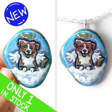 Load image into Gallery viewer, a small beach stone, hand painted with the portrait of a smiling Australian Shepherd dog, as an angel with wings and halo, sitting on fluffy clouds against a blue sky. this piece is available as a stone keepsake or pendant necklace
