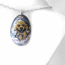 Load image into Gallery viewer, a small beach stone hand painted with the portrait of a brown poodle as an angel, sitting in the clouds against a blue sky. available as a keepsake or pendant necklace
