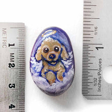 Load image into Gallery viewer, a small beach stone hand painted with the portrait of a brown poodle as an angel, sitting in the clouds against a blue sky. available as a keepsake or pendant necklace
