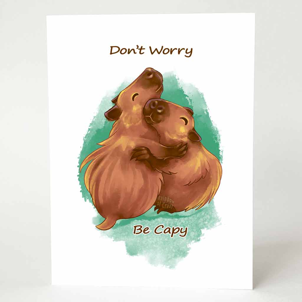 a greeting card with an illustration of two capybaras hugging. the front of the card reads 