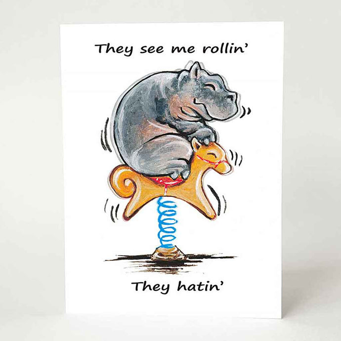 a greeting card with a smiling hippo, riding an orange rocking horse. the card reads, 
