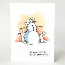 Load image into Gallery viewer, greeting card with an illustration of a smiling snowman with three small white rabbits helping to build it. on the bottom, the card says, &quot;do you want to build a snowman?&quot;
