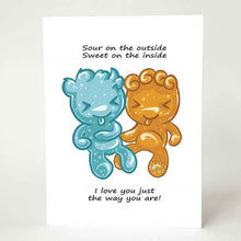 Load image into Gallery viewer, A greeting card with art of two sour candies in the shape of people (one blue, one orange), the card reads, &quot;Sour on the outside / Sweet on the inside / I love you just the way you are!&quot;
