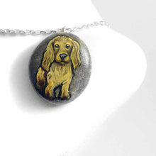 Load image into Gallery viewer, a beach stone hand painted with the portrait of a light brown cocker spaniel dog. this piece is available as a rock keepsake, or pendant necklace
