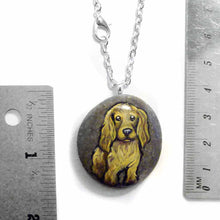 Load image into Gallery viewer, a beach stone hand painted with the portrait of a light brown cocker spaniel dog. this piece is available as a rock keepsake, or pendant necklace
