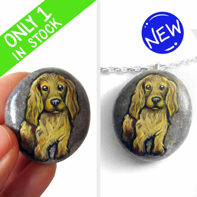 a beach stone hand painted with the portrait of a light brown cocker spaniel dog. this piece is available as a rock keepsake, or pendant necklace