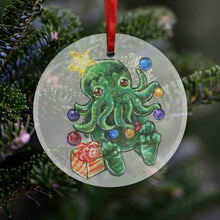 Load image into Gallery viewer, a round glass ornament, printed with an illustration of cthulhu as a christmas tree, with ornaments hanging on its tentacles, a star on its head, and a present by its feet
