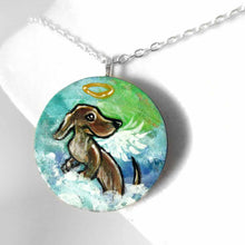 Load image into Gallery viewer, a lightweight wood disc, hand painted with the portrait of a dachshund, as an angel, sitting on fluffy clouds against a green and blue sky. available as a keepsake or pendant necklace 
