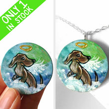 Load image into Gallery viewer, a lightweight wood disc, hand painted with the portrait of a dachshund, as an angel, sitting on fluffy clouds against a green and blue sky. available as a keepsake or pendant necklace 
