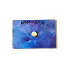 Load image into Gallery viewer, back of a blue and purple wood magnet, with a small circular magnet in the center. at the top reads &quot;RainbowofCrazy&quot;
