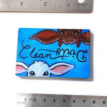 Load image into Gallery viewer, blue wood magnet, hand painted, bottom features a brown goat with little red horns with the word &quot;Dirty&quot; above them. at the top, upside down is a white goat, with the word &quot;clean&quot; above them
