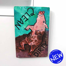 Load image into Gallery viewer, wood magnet on a dishwasher, hand painted with a pig with the word CLEAN (upside down) next to its face at the top. the second half of the pig is muddy, and written next to its body, DIRTY.
