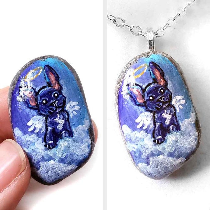 a small beach stone painted with dog art: a black french bulldog as an angel in the clouds. available as a stone keepsake or a pendant necklace