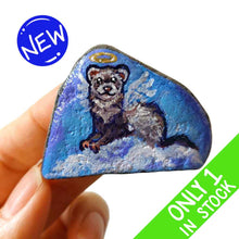 Load image into Gallery viewer, a small beach stone, painted with a portrait of a ferret as an angel in the clouds
