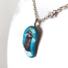 Load image into Gallery viewer, a small beach stone, painted with a smiling ferret angel, with halo and wings, on top of clouds, against a blue sky. available as a keepsake, magnet or pendant necklace
