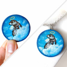 Load image into Gallery viewer, a wood circle keepsake, painted with a portrait of a ferret as an angel, with halo, and wings, sitting on clouds agains a blue background. available as a mini painting or pendant necklace
