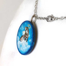 Load image into Gallery viewer, a wood circle keepsake, painted with a portrait of a ferret as an angel, with halo, and wings, sitting on clouds agains a blue background. available as a mini painting or pendant necklace
