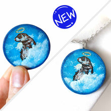 Load image into Gallery viewer, a wood circle keepsake, painted with a portrait of a ferret as an angel, with halo, and wings, sitting on clouds agains a blue background. available as a mini painting or pendant necklace
