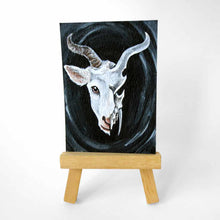 Load image into Gallery viewer, an aceo features a split image: a white horned goat&#39;s head on the left side, and a darker, stylized goat skull on the right
