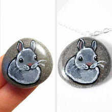 Load image into Gallery viewer, a small beach stone, hand painted with the portrait of a gray rabbit. available as a keepsake or pendant necklace
