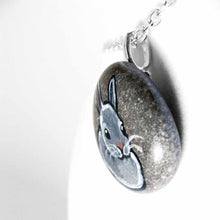 Load image into Gallery viewer, a small beach stone, hand painted with the portrait of a gray rabbit. available as a keepsake or pendant necklace
