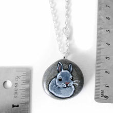 Load image into Gallery viewer, a small beach stone, hand painted with the portrait of a gray rabbit. available as a keepsake or pendant necklace
