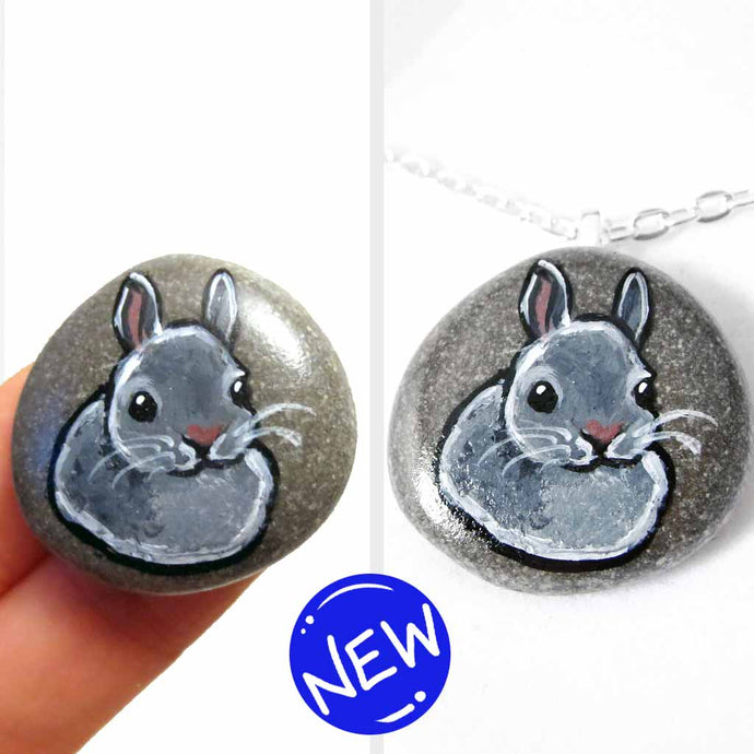 a small beach stone, hand painted with the portrait of a gray rabbit. available as a keepsake or pendant necklace