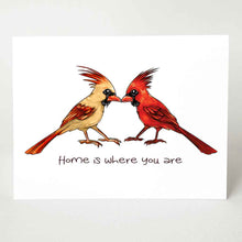 Load image into Gallery viewer, a greeting card featuring an illustration of two cardinals, one female, one male, beaks just touching. it reads, &quot;Home is where you are&quot;.
