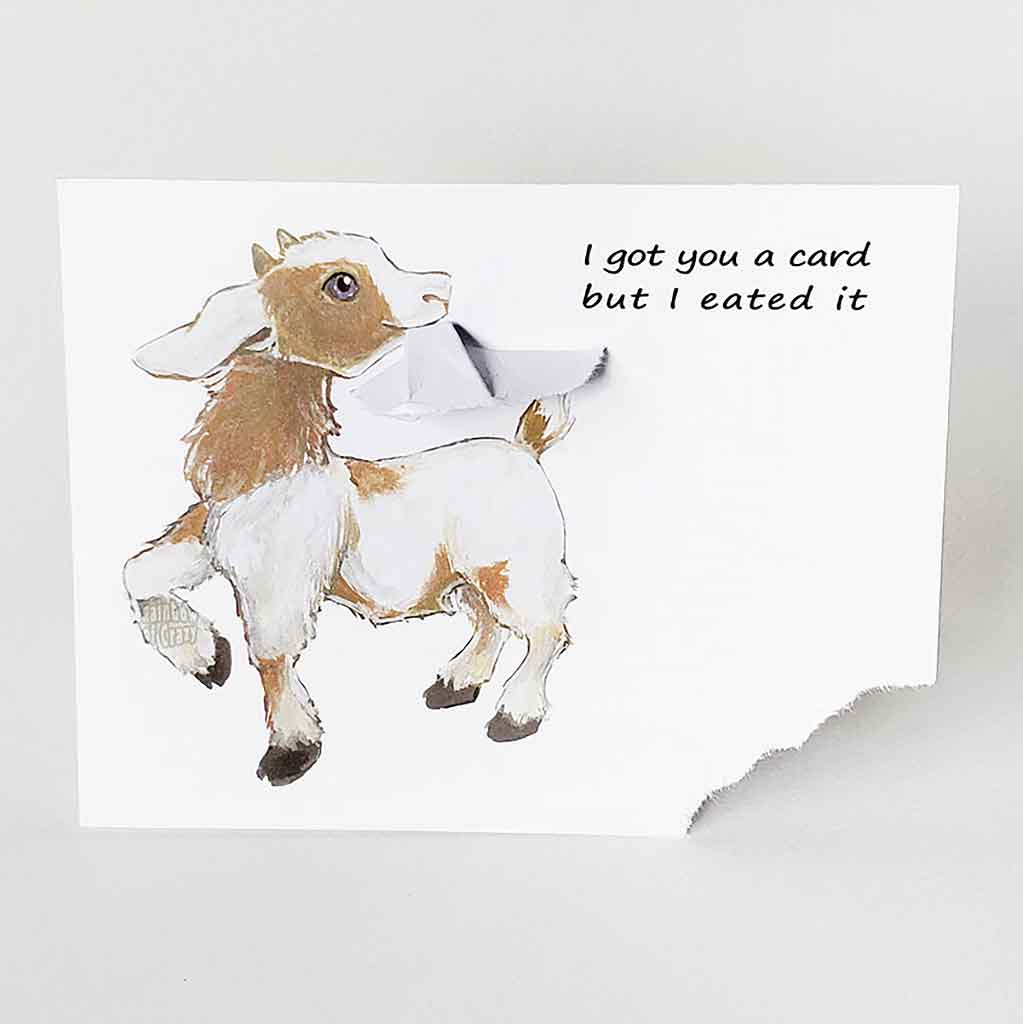 a funny greeting card with a goat on the front, with the bottom right corner of the card ripped and hanging from its mouth. the card reads, 