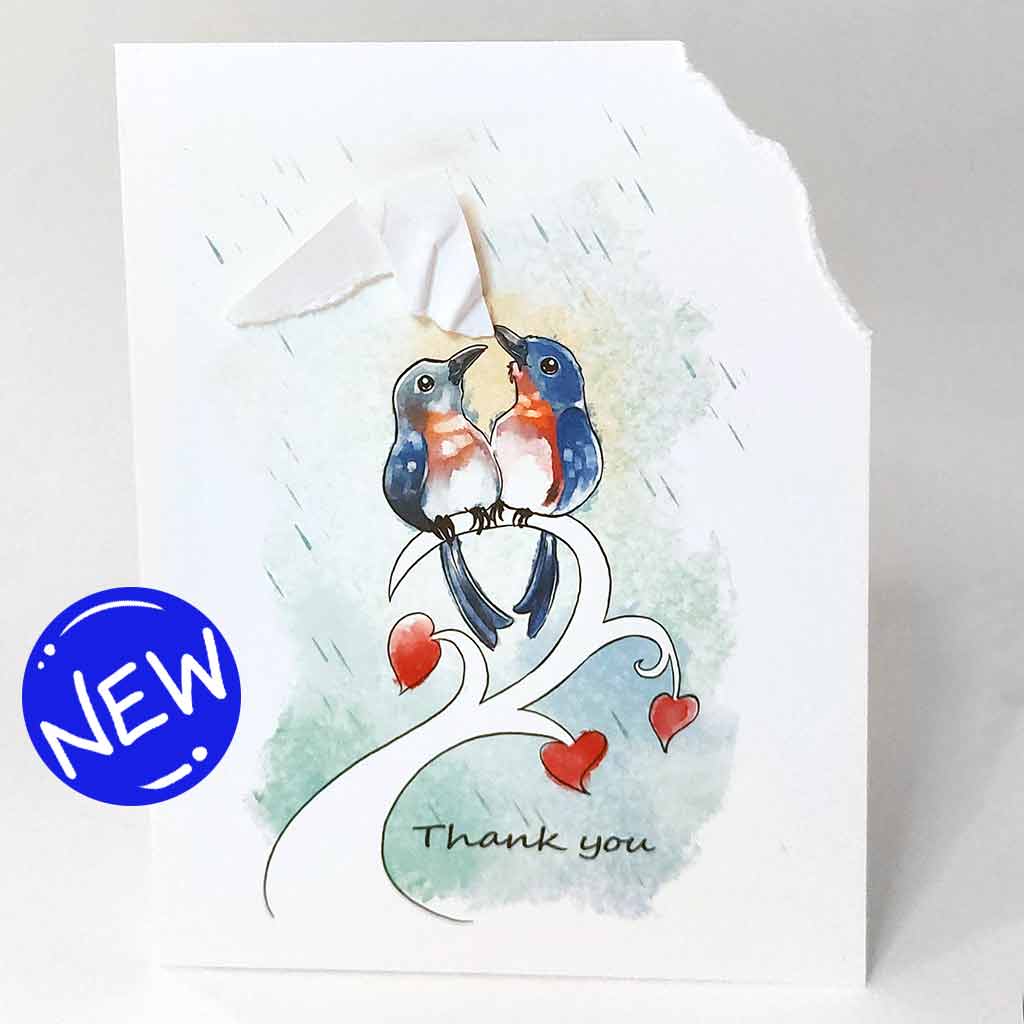 a handmade greeting card wtih an illustration of two bluebirds on a tree branch. the top right corner of the card is ripped off and hangs from one bluebird's mouth, as it holds it up above the other bird, protecting it from the rain. the card says, 