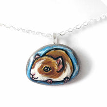 Load image into Gallery viewer, a small beach stone hand painted with a portrait of a guinea pig against a blue background. Available as a keepsake stone or pendant necklace
